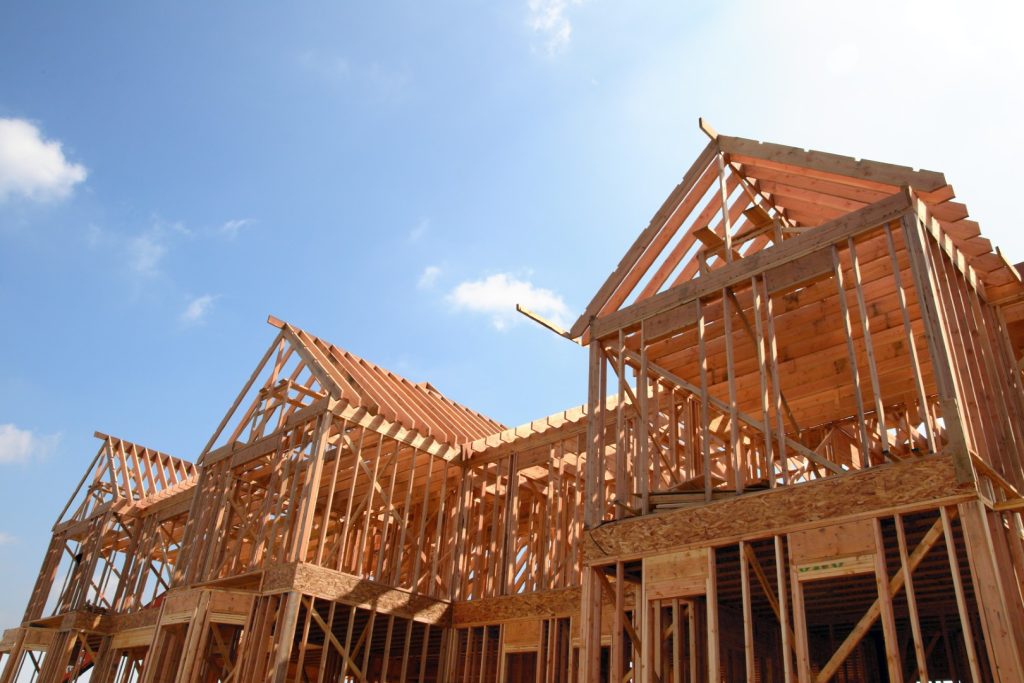 Wooden frame of a new house under construction against a bright sunny sky