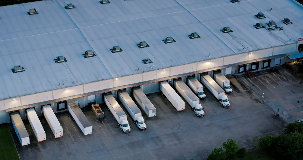 Aerial shot of large semi-trucks parked in a warehouse in Houston, Texas in the evening.